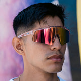 Model wearing LosReyes Prime Galaxy Venus wraparound sports sunglasses with pink mirrored shield lenses and clear frame, styled for athletic and casual wear.