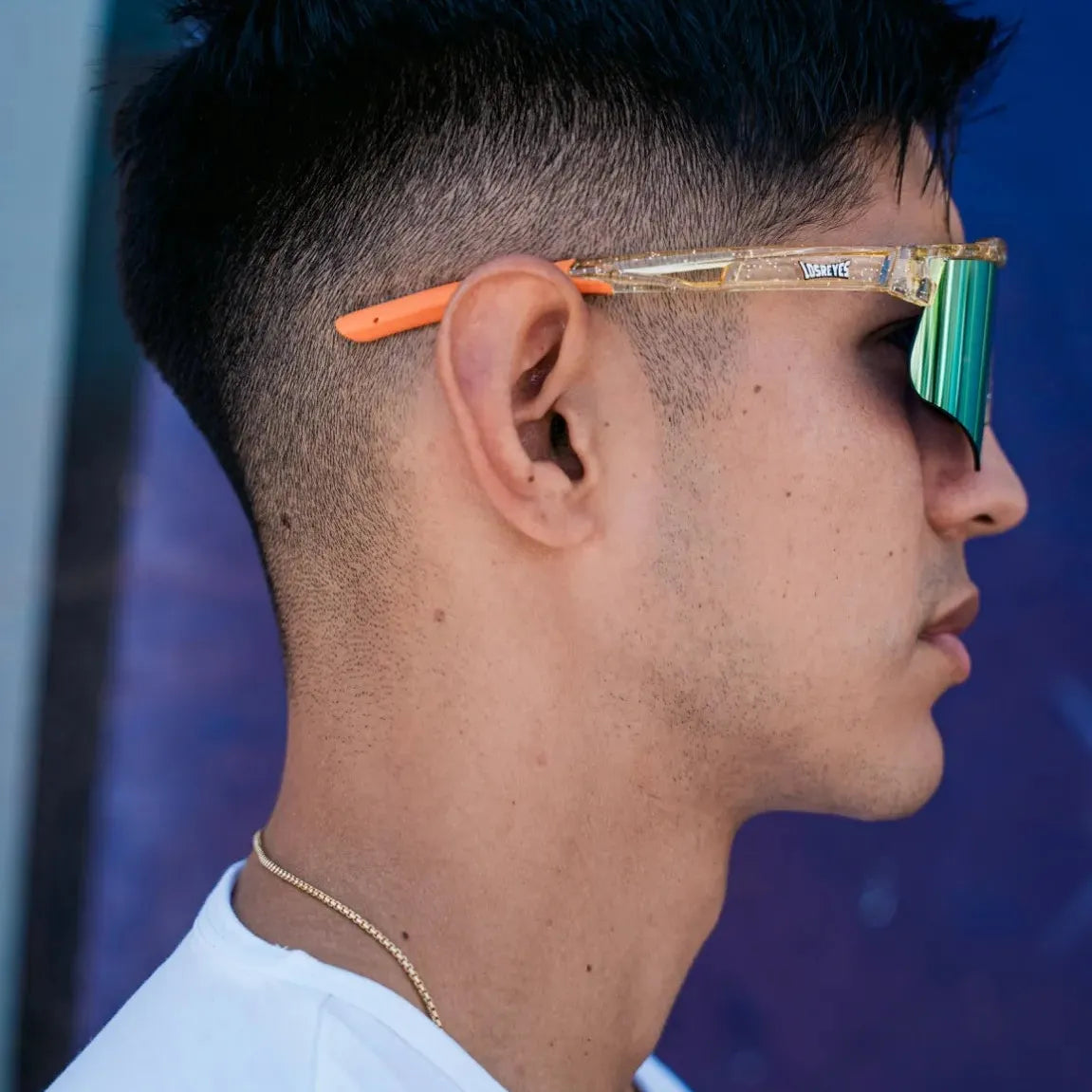 Side lifestyle shot of LosReyes Prime Galaxy Sun yellow sunglasses showcasing their UV400 mirrored lenses, orange rubberized tips, and translucent performance frame for all-day outdoor activity.