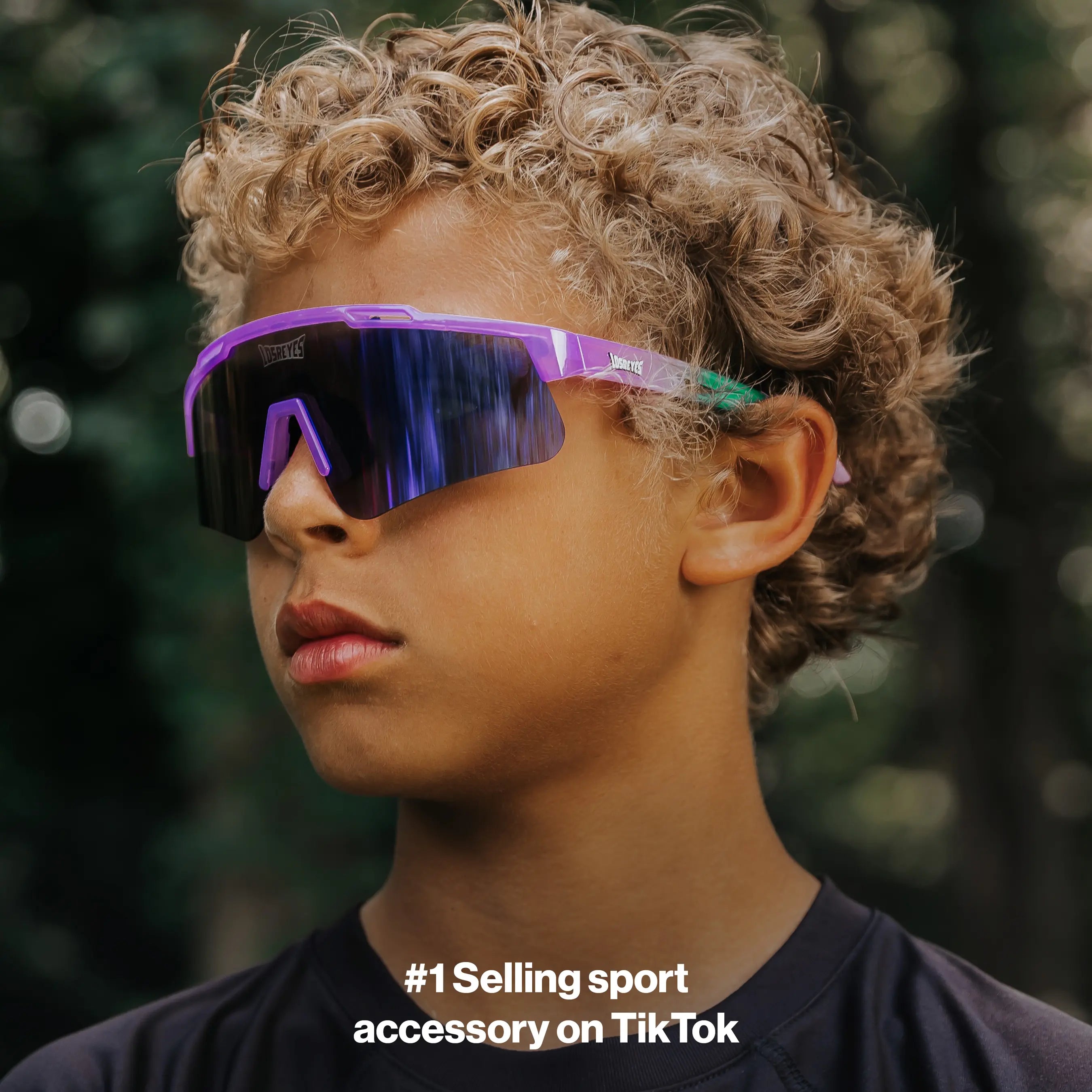 Youth lifestyle photo of LosReyes Prime Jurassic Brontosaurus sunglasses in purple and green with a mirrored shield lens, designed for young athletes with a wraparound fit and outdoor performance protection.