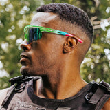 Side profile lifestyle photo of LosReyes Prime Jurassic Pterodactyl sunglasses with a green and blue wraparound frame, mirrored shield lens, and aerodynamic sport fit. Designed for intense outdoor performance, training, and UV400 protection.