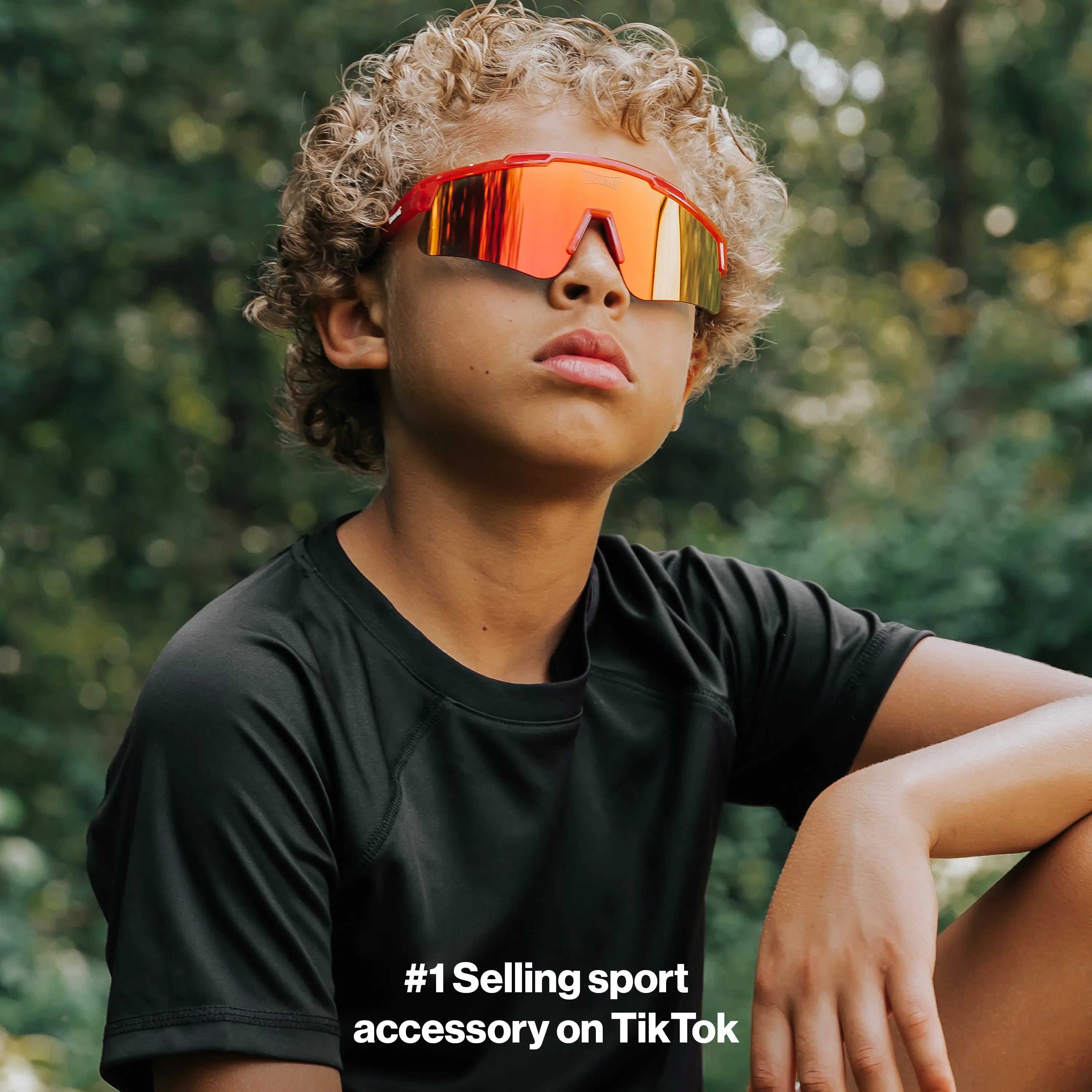 Youth lifestyle photo of LosReyes Prime Jurassic T-Rex red sports sunglasses with mirrored shield lens and wraparound fit, engineered for active kids, UV protection, and outdoor adventure performance.
