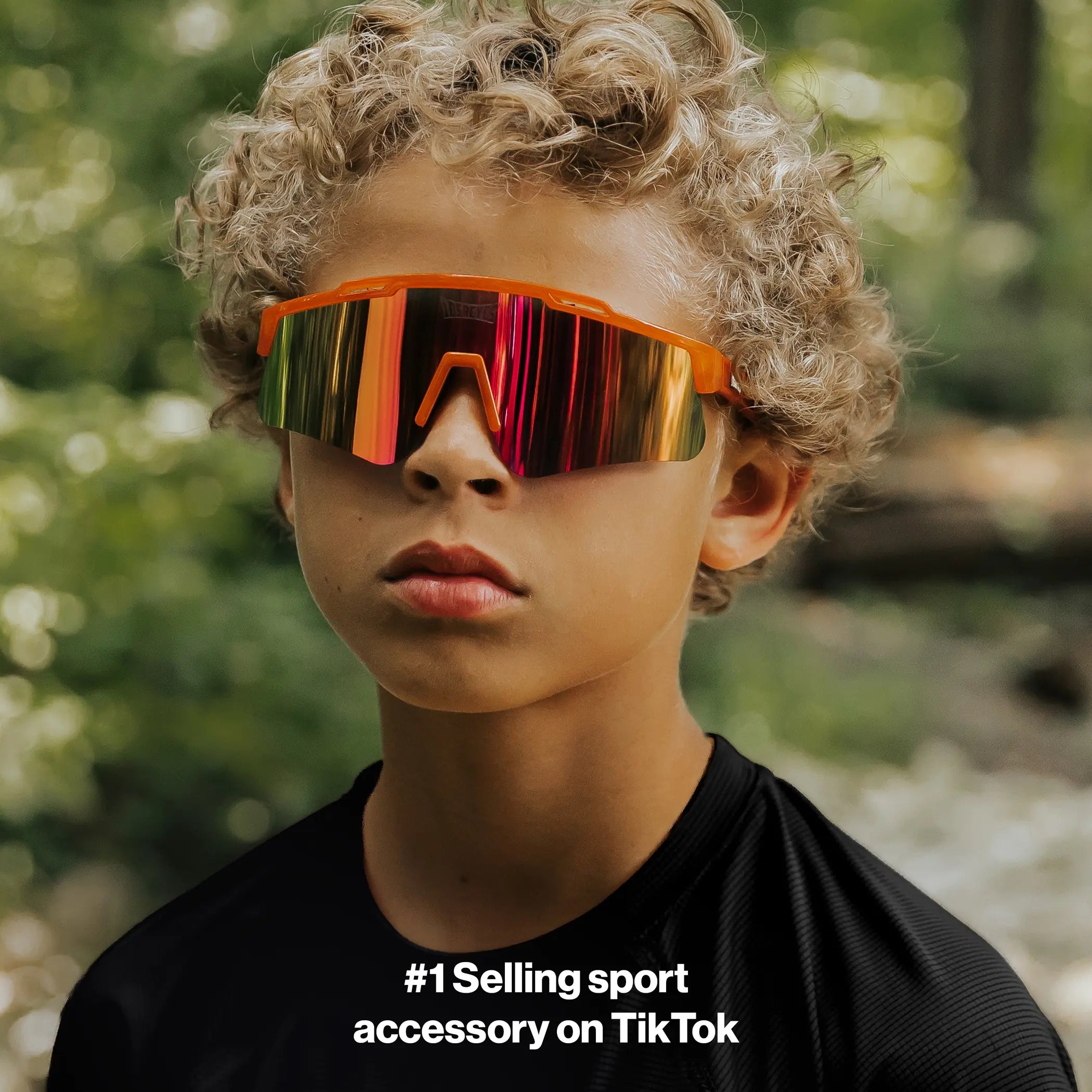 Youth lifestyle image of LosReyes Prime Jurassic Triceratops sunglasses in vibrant orange with a mirrored shield lens and wraparound sport frame, designed for outdoor performance, active wear, and full UV protection.