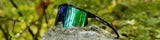 LosReyes polarized outdoor sunglasses resting on a forest rock surrounded by greenery.