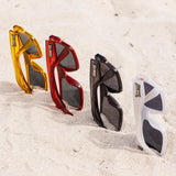 LosReyes lifestyle sunglasses lineup in yellow, red, black, and white on the sand, showcasing bold Miami design, UV400 lenses, and durable TR90 frames.