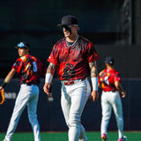 Max Clark walking across the outfield in a red alternate jersey and white pants, wearing black LosReyes SHOWTIME sunglasses during team drills.