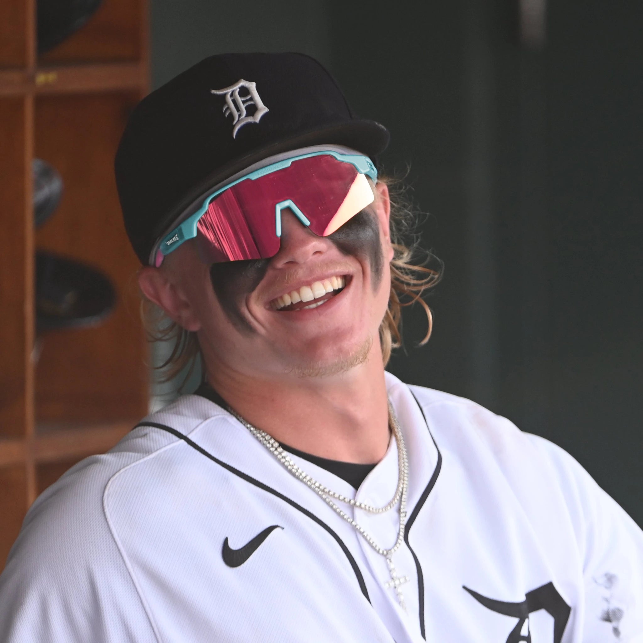Max Clark sitting in the Detroit Tigers dugout, laughing with pink-tinted LosReyes SHOWTIME sunglasses and heavy eye-black across his cheeks.