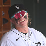 Max Clark sitting in the Detroit Tigers dugout, laughing with pink-tinted LosReyes SHOWTIME sunglasses and heavy eye-black across his cheeks.