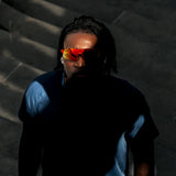 Top-down dramatic shot of model wearing Edge Lava sunglasses with red-orange mirrored shield lenses in low light.