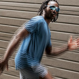 Model in motion wearing Edge Ocean sunglasses with blue mirrored lenses, captured in an urban running scene.