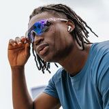 Model adjusting Edge Royal sunglasses with purple mirrored lenses during outdoor activity.