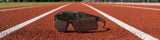 LosReyes Prime Galaxy sunglasses in Moon colorway with smoke lens and translucent frame resting on a red running track lane