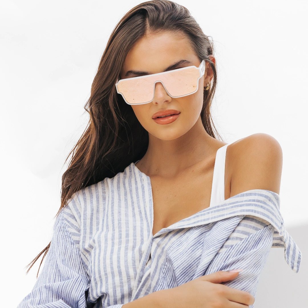 Woman wearing oversized pink lens and white frame Athena Omega collection sunglasses from LosReyes with a plain background