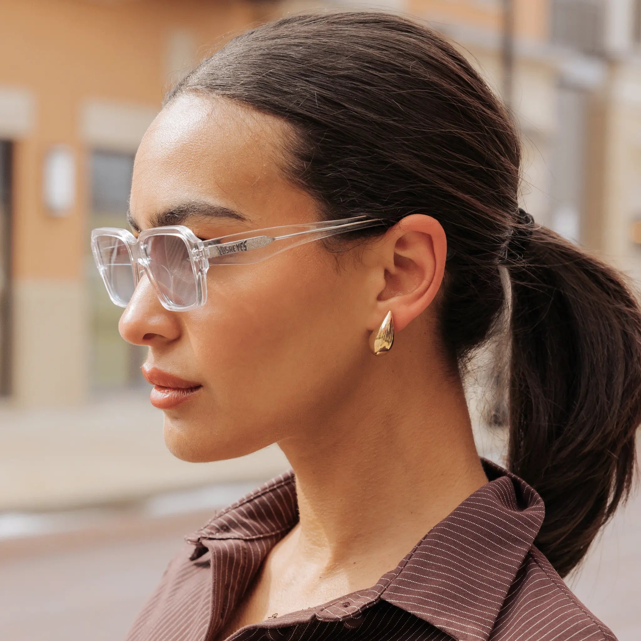 Woman wearing LosReyes Opus Monaco transparent frame sunglasses with gold earrings – clear luxury fashion eyewear