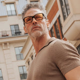 Man wearing LosReyes Opus Positano black frame sunglasses with orange lenses walking in city street