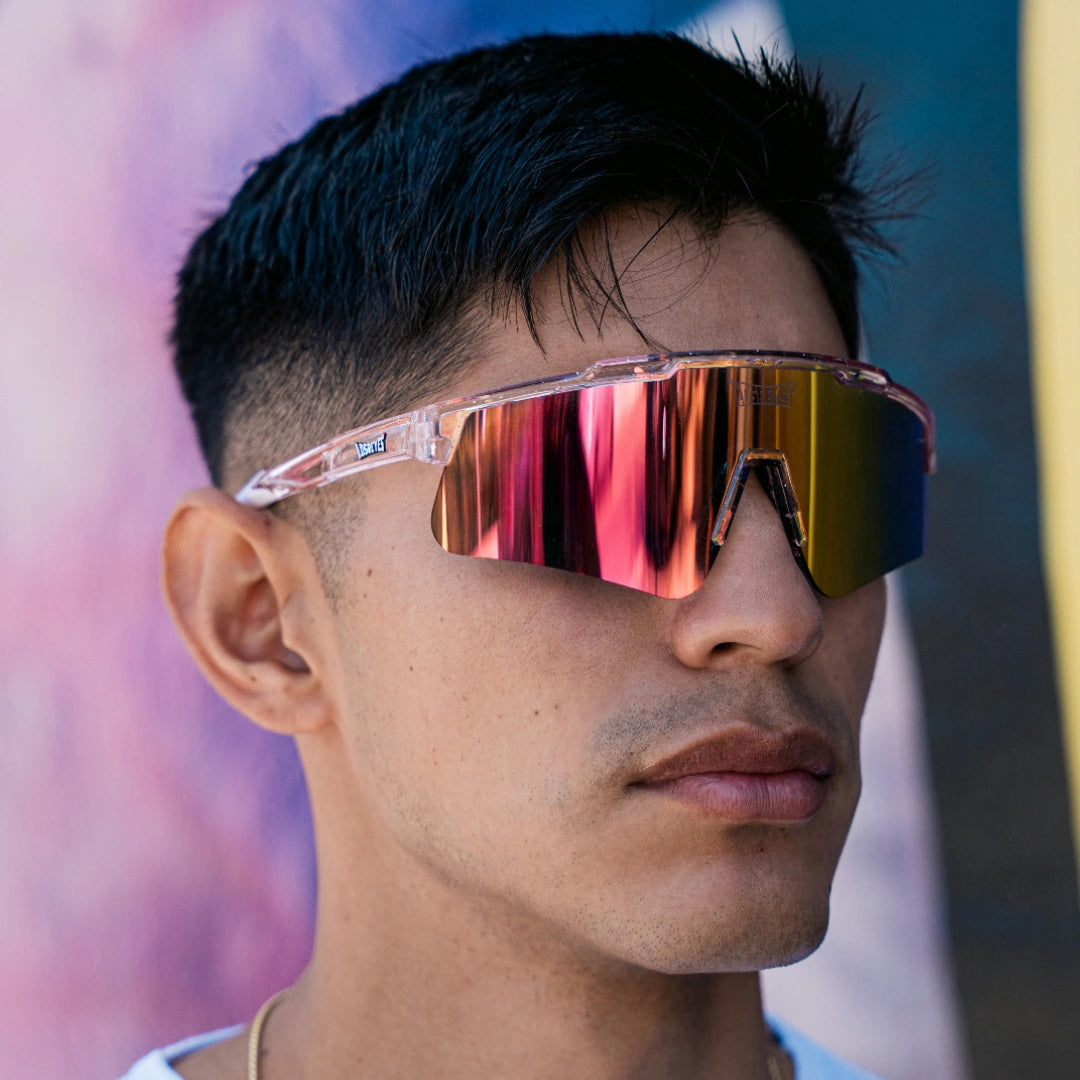 Model wearing LosReyes Prime Galaxy Venus wraparound sports sunglasses with pink mirrored shield lenses and clear frame, styled for athletic and casual wear.