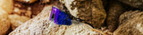 LosReyes polarized sport sunglasses with purple and blue mirrored lenses resting on natural rocks outdoors