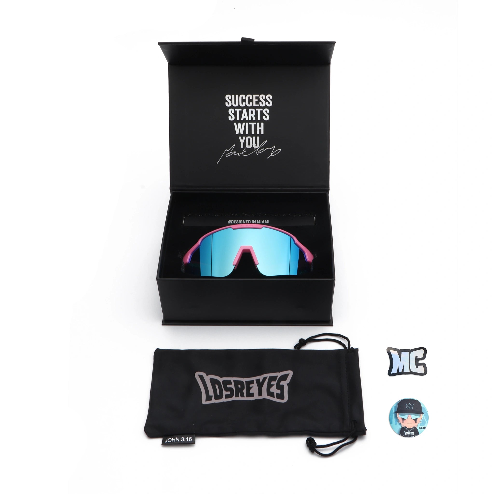 Flat lay of LosReyes Showtime Max Clark Original sunglasses with premium packaging, microfiber pouch, collector stickers, and UV400 mirrored lens showcased in black box with inspirational quote. 