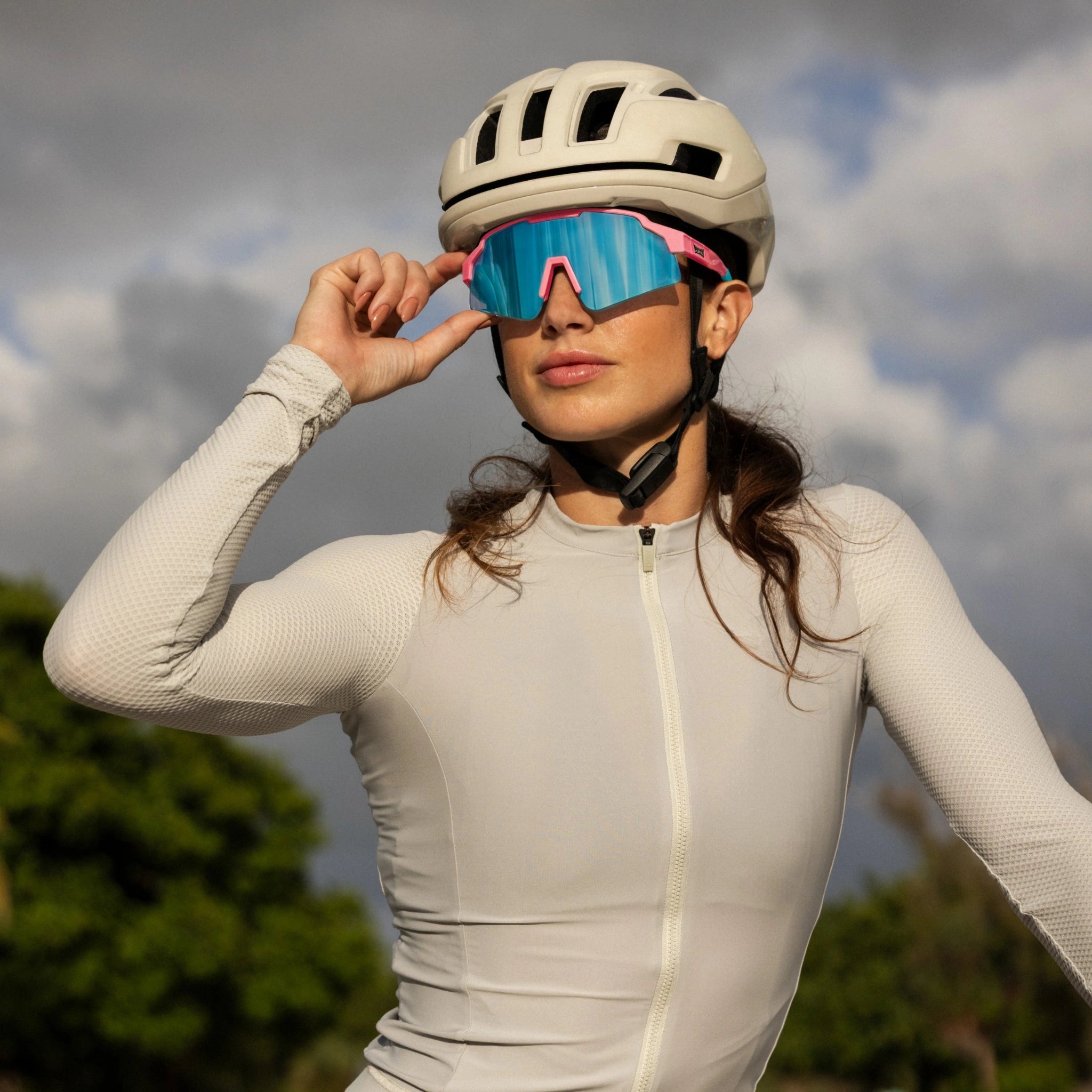 LosReyes SHOWTIME Vice cycling sunglasses with mirrored blue lens and pink frame, worn by cyclist adjusting fit before ride