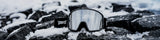 LosReyes snow goggles with mirrored lens resting on snow-covered rocks in a winter mountain environment