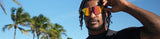 athlete outdoors adjusting Los Reyes polarized sports sunglasses with red-gold mirrored lenses, UV protection durable shades designed for basketball and active sports lifestyle