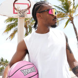Athlete holding pink Los Reyes basketball on outdoor court, wearing polarized sports sunglasses with UV protection, durable shades made for sports
