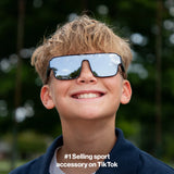 Boy wearing LosReyes youth Hades sport shield sunglasses in black with silver mirror lens, front view outdoors