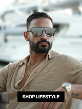 Man wearing LosReyes oversized luxury sunglasses sitting near yachts at a marina 